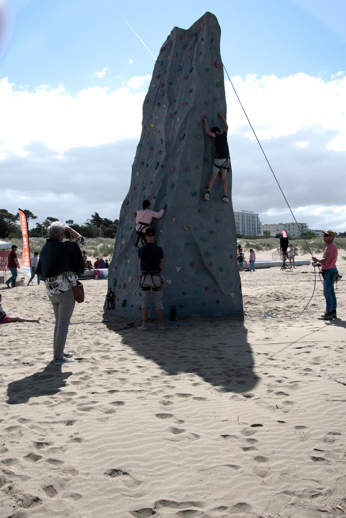 L'une des deux tours d'escalade dressée sur le sable, un grimpeur en paroi
